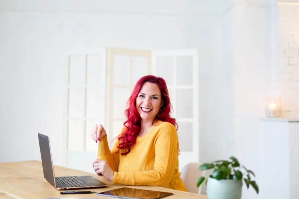 Sabrina Amels im gelben Pullover am Schreibtisch mit Laptop, ein Branding-Foto aus ihrer Zeit als Werbequeen.